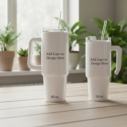 Two white travel mugs with handles on a wooden surface, surrounded by plants.